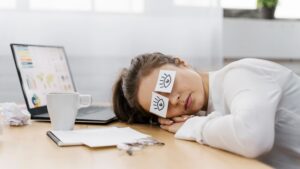 Vrouw met slaaptekort op werkplek, symptoom van gebrek aan persoonlijk slaapadvies